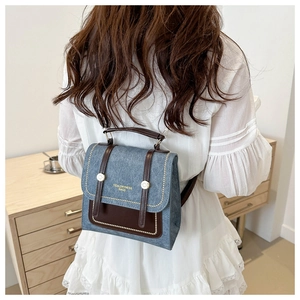 Retro denim backpack with brown leather trim worn by model in minimalist setting