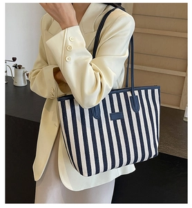 Detail of blue and white striped tote bag with leather tag shown on a model shoulder