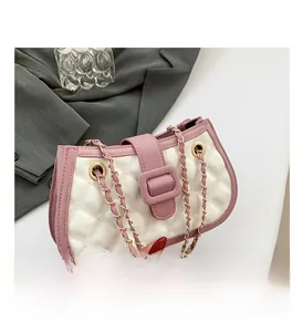 Detailed view of white quilted leather bag with pink contrast trim and gold chain strap