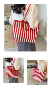 Detail of red and white striped canvas tote bag with red leather handles and trim