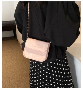 Close-up of pink chain crossbody bag with gold rich rabbit logo and metal strap