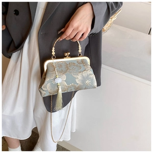 Detail der Seiden-Vintage-Handtasche mit goldener Blumenstickerei und weißem Quastenanhänger