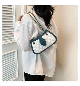 Close-up of quilted white leather bag with dark green trim and metal chain strap