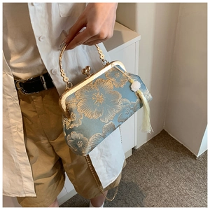 Detail of light blue floral embroidery on vintage clasp handbag with gold metal handle
