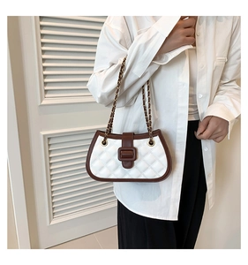 Detail of white quilted handbag with brown trim and golden chain strap on model