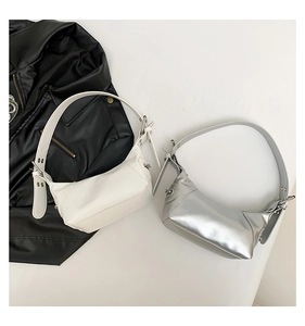 Detail of minimalist half-moon shoulder bags in cream white and metallic silver leather