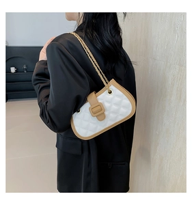 Quilted white shoulder bag with khaki trim and gold chain strap on a black blazer