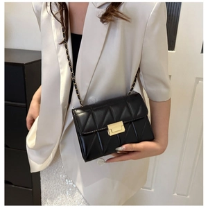 Sac bandoulière matelassé noir avec fermoir doré et bandoulière chaîne sur blazer