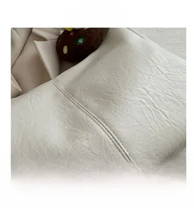 Detailed macro view of cream leather tote bag featuring double stitching and wrinkled texture