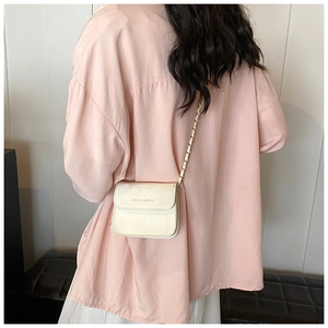 Chic cream mini crossbody bag with gold chain strap shown on model back view
