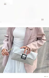 Detail of silver textured clutch bag with black square buckle and stylish wristlet strap