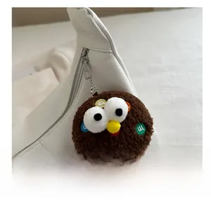 Detailed view of a brown plush charm with colorful patches on a white leather tote bag