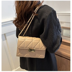 Sac bandoulière en cuir matelassé beige avec chaîne et fermoir doré porté par un mannequin