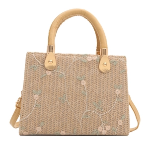 Straw tote bag with floral embroidery and leather handles on a white background
