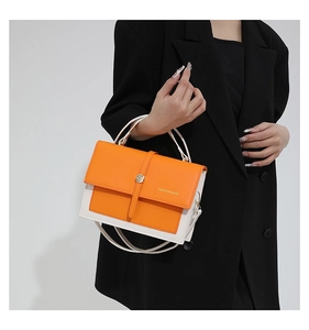 Detail of orange and white leather shoulder bag with gold twist lock on black blazer