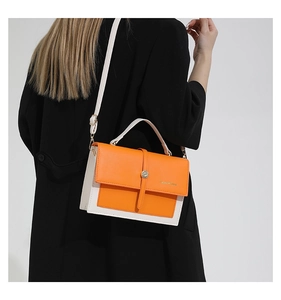 Detail of orange and white crossbody bag featuring a metal buckle on black suit