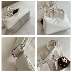 Close-up of litchi grain texture and plush pendant on white soft PU shoulder bag