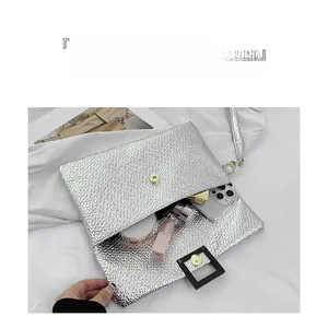 Detailed view of silver woven clutch bag with gold magnetic clasp and spacious interior
