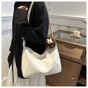 Detail of white wrinkled leather tote bag with a cute brown plush cookie charm pendant