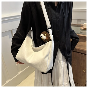 Close-up of white textured leather tote bag with a cute brown plush bear pendant