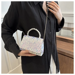 Close-up of holographic sequin handbag with pearl handle and metal chain detail