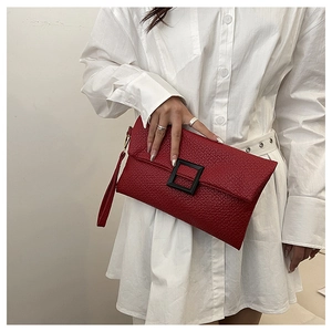 Detail of red lychee pattern envelope clutch bag with black square buckle and strap