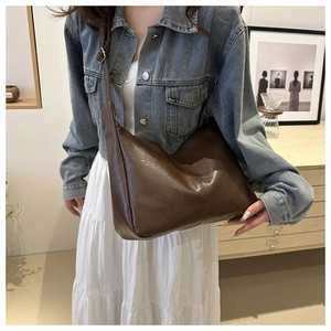 Deep brown minimalist faux leather tote bag with adjustable strap in a warm lifestyle scene