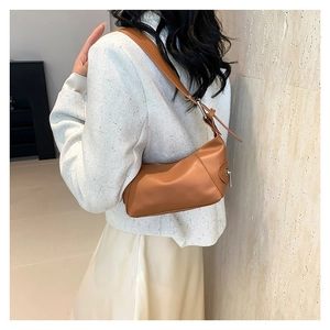 Brown leather baguette shoulder bag for women worn with a white tweed jacket