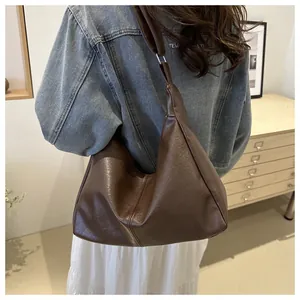 Detailed view of brown PU leather tote bag with vertical stitching on a female model