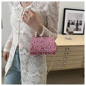 Detailed shot of pink sequined handbag featuring a pearl handle and gold chain strap