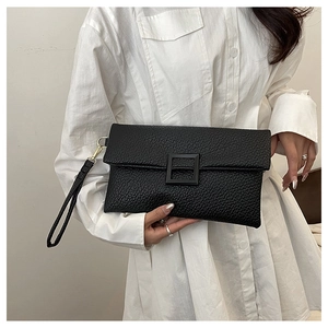 Detail of black lychee textured leather clutch bag with a large matte square buckle