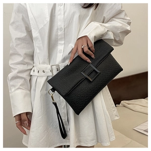 Close-up of black envelope clutch with litchi texture and gold metal wristlet buckle