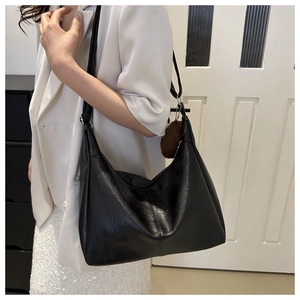Detail of black large capacity hobo tote bag with soft leather texture and plush charm