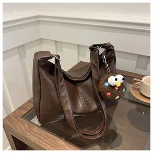 Detail view of coffee brown soft PU tote bag with lychee texture and cute plush charm