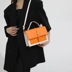 Fashionable orange and white contrast crossbody bag worn with black suit for summer