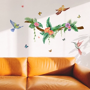 Tropical wall decals with birds and flowers displayed above a stylish orange sofa