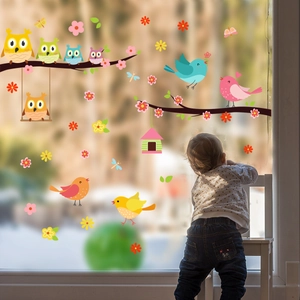 Toddler by window decorated with colorful owl, bird, and tree branch static wall stickers