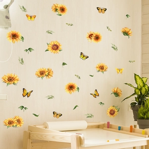 Dettaglio di adesivi murali con girasoli e farfalle su una parete interna color crema