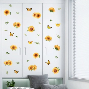 Dettaglio di adesivi murali con girasoli e farfalle applicati su un armadio bianco
