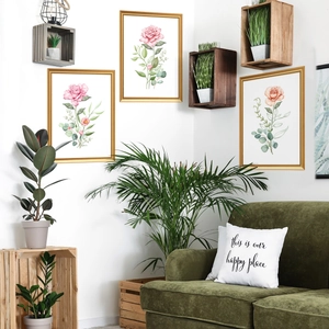 Detailed view of floral watercolor wall art set in gold frames over a green sofa