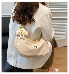 Détail du sac demi-lune en nylon beige avec breloque nuage et étiquette tissée