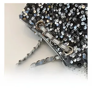 Close-up of sparkling silver sequins and metal chain hardware on a stylish handbag