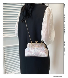 Detail of vintage jacquard frame bag with golden chain strap and floral pattern