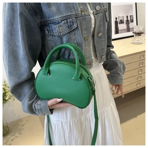 Detail view of a green leather mini satchel with double handles and a long shoulder strap