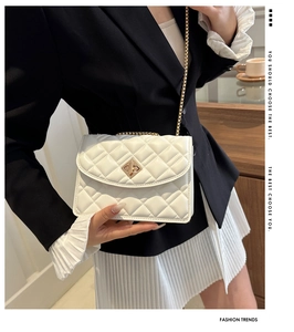 Close-up of white quilted leather texture with gold metal buckle and chain strap