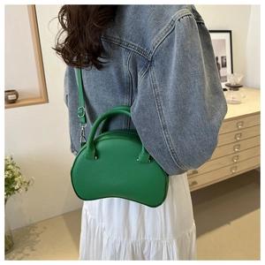 Detailed side view of a green semi-circle crossbody bag with adjustable strap and silver hardware