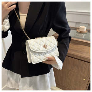 Close-up of white quilted crossbody bag with gold chain strap worn by a model