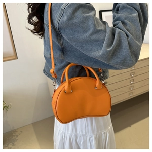 Detailed view of an orange shell bag worn over the shoulder with a blue denim jacket