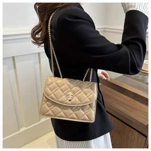 Close-up of beige quilted crossbody bag with gold chain strap and metal twist lock