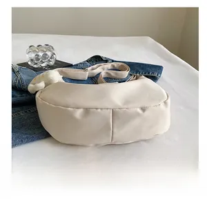 Détail du sac demi-lune en nylon beige avec bandoulière large et breloque nuage doux